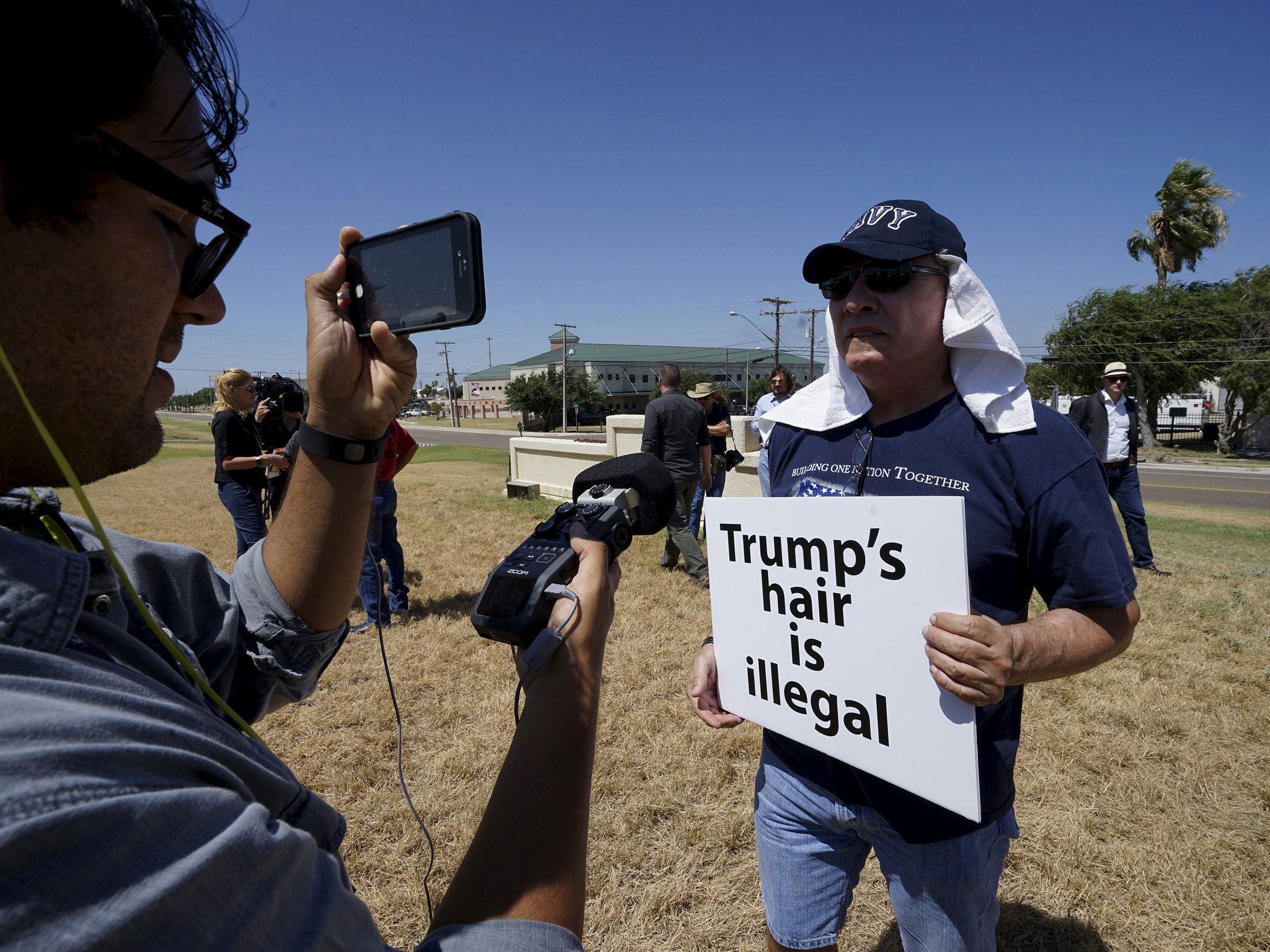 A protester is interviewed outside the airport as he awaits the arrival of Republican presidential candidate Donald Trump