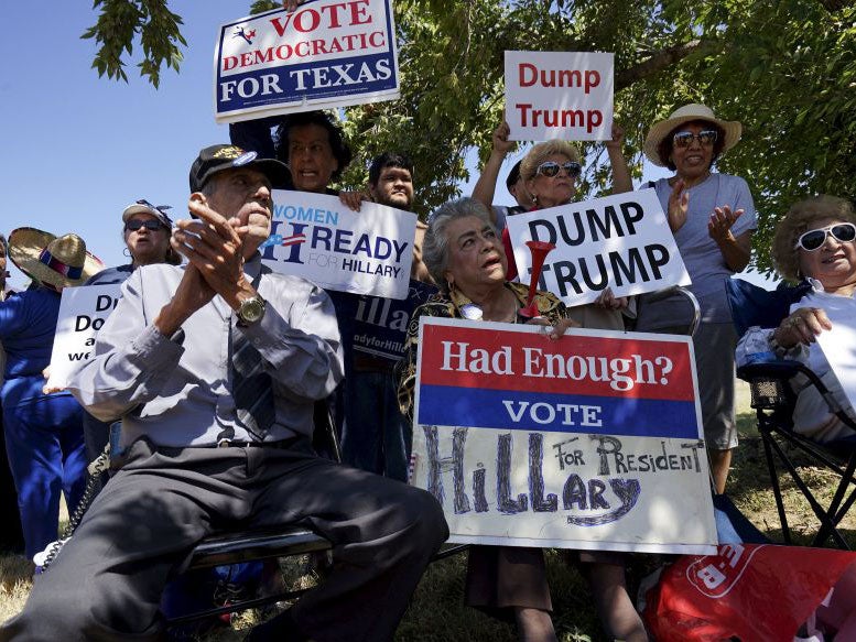 People hold signs as they gather to protest the visit of Republican presidential candidate Donald Trump