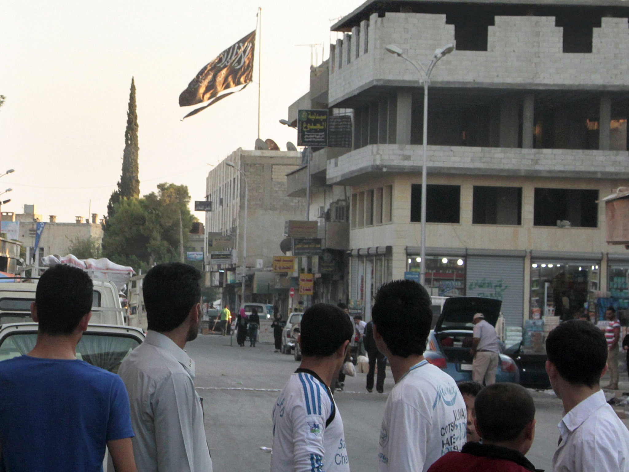 A group of men look at a large black Jihadist flag in Raqqa, where Adam Brookman worked as a medic