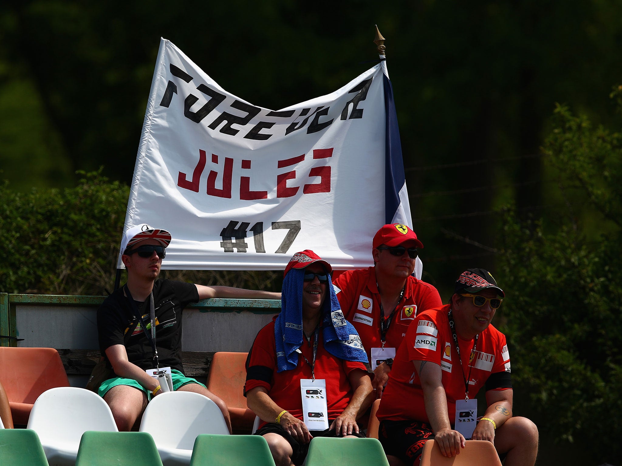 Fans sit in front of a tribute banner to Jules Bianchi