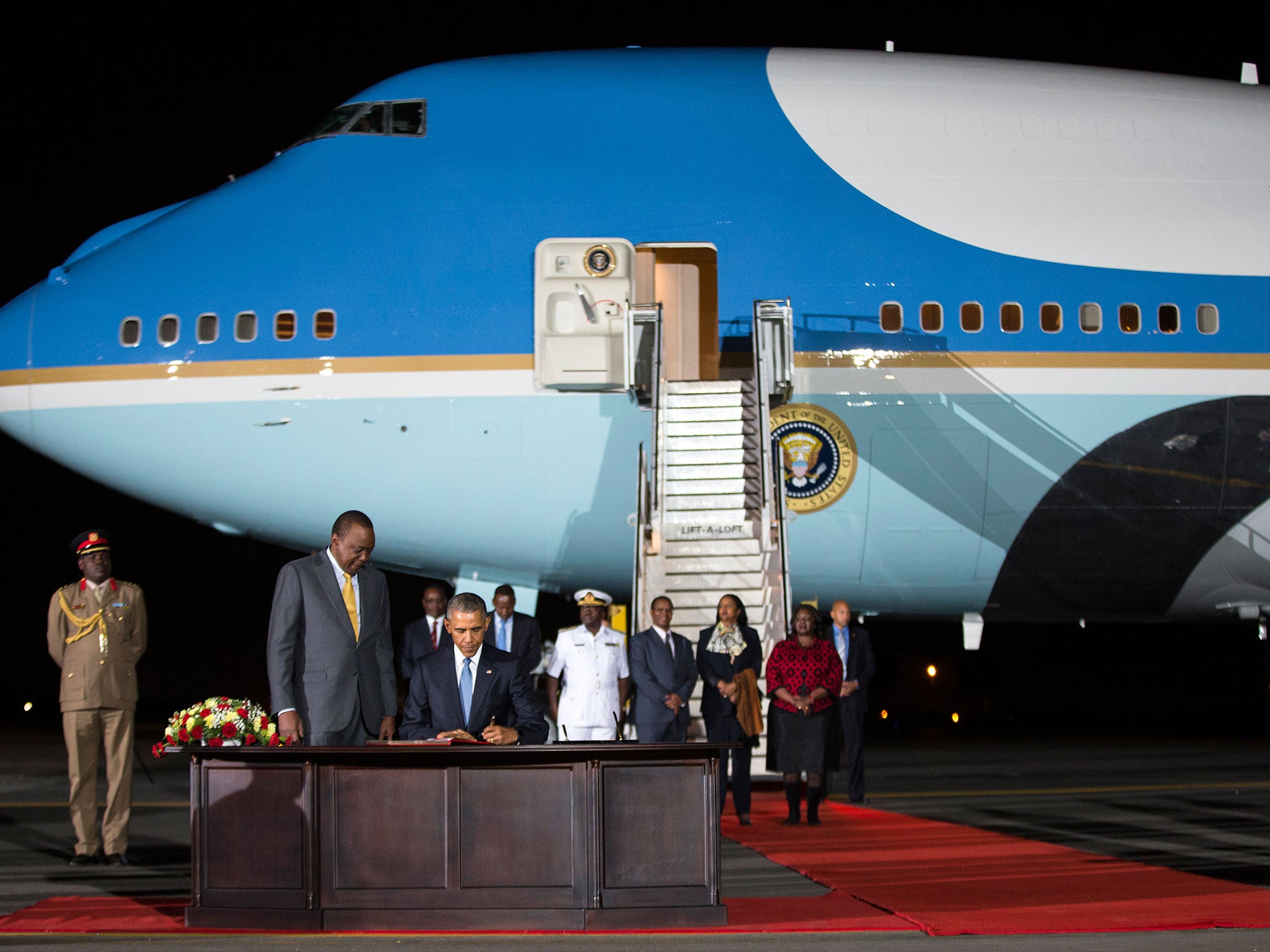 Kenyan President Uhuru Kenyatta, left, watches as President Barack Obama signs a guest book after arriving at Kenyatta International Airport
