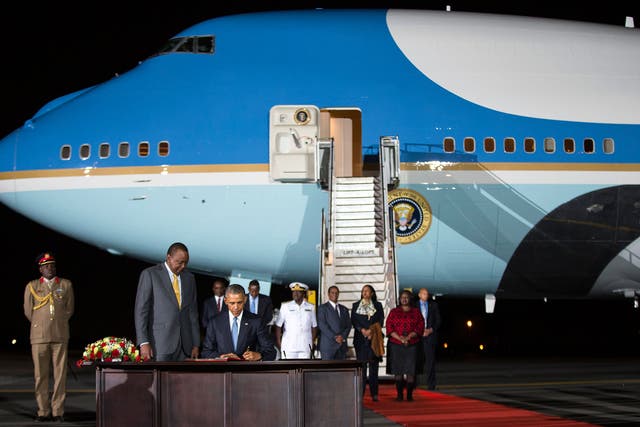Kenyan President Uhuru Kenyatta, left, watches as President Barack Obama signs a guest book after arriving at Kenyatta International Airport