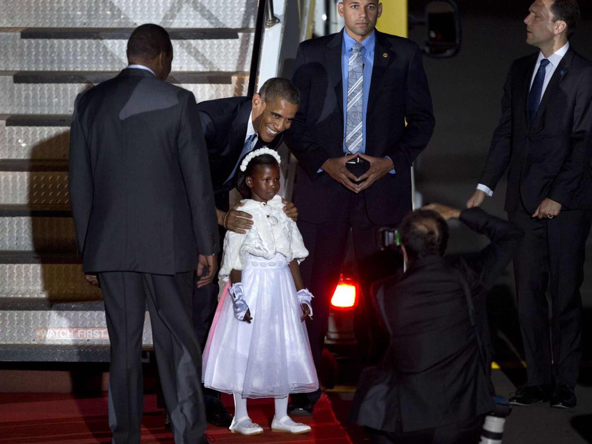 Barack Obama poses for a photograph with a girl who gave him flowers on his arrival at the Jomo Kenyatta International Airport in Nairobi