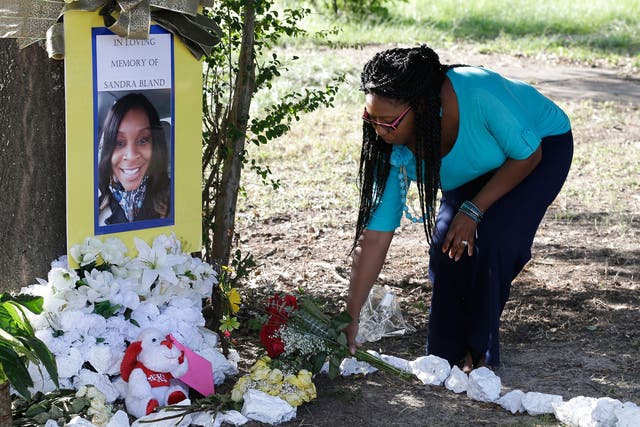 Jeanette Williams places a bouquet of roses at a memorial for Sandra Bland near Prairie View A&M University, Tuesday, July 21, 2015, in Prairie View, Texas