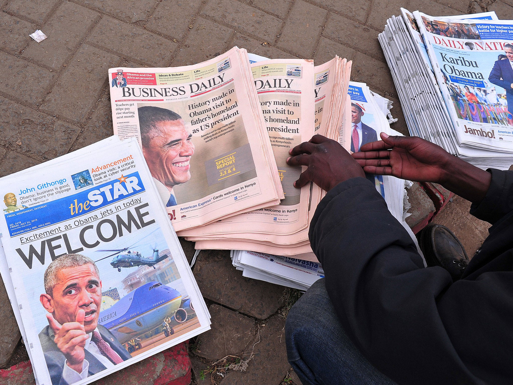 A Kenyan newspaper vendor lays out papers marking Obama's first visit the country as President