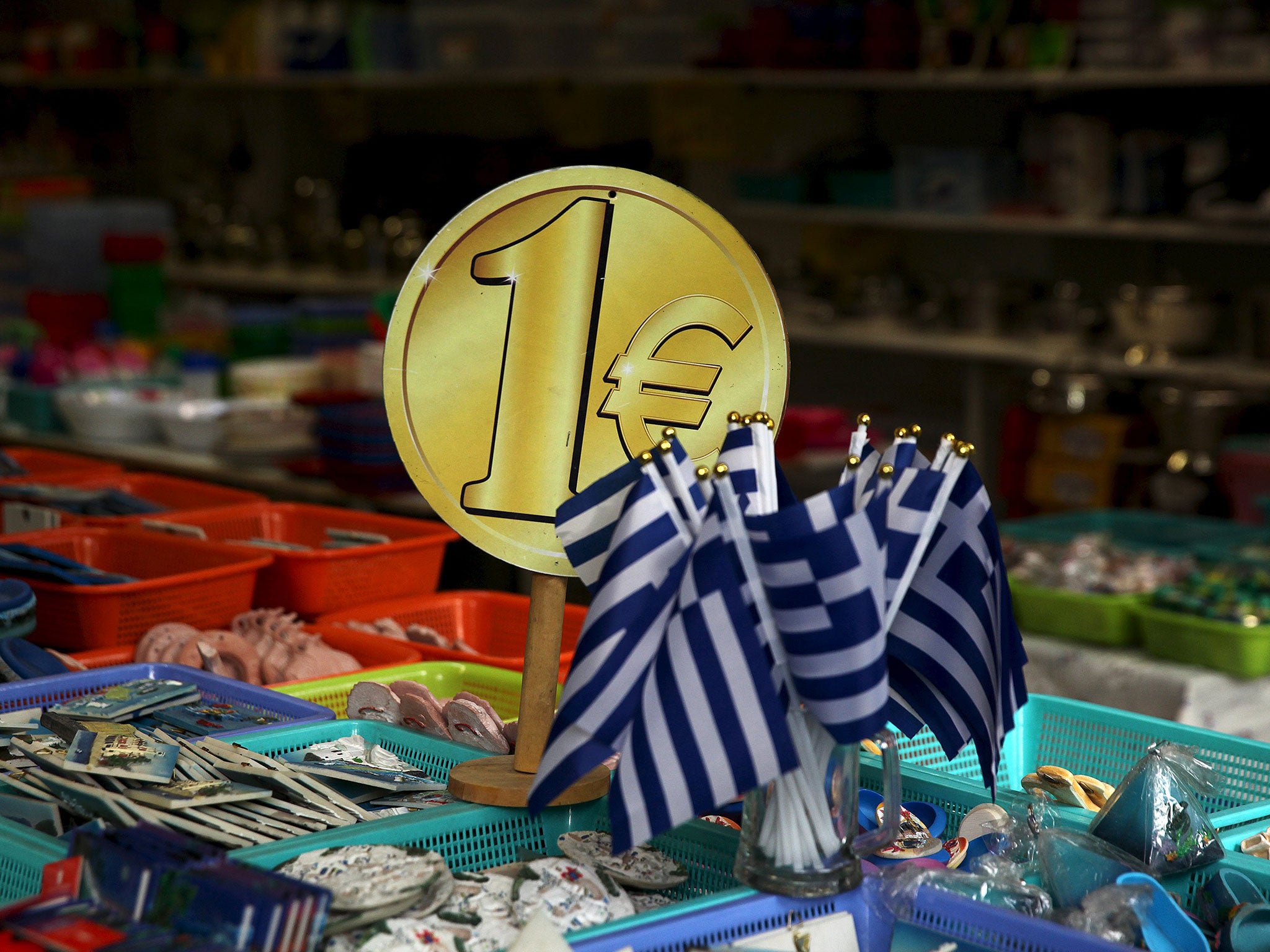 Greek flags for sale for one euro in Athens: capital controls are set to stay for months, while talks on a third bailout begin today