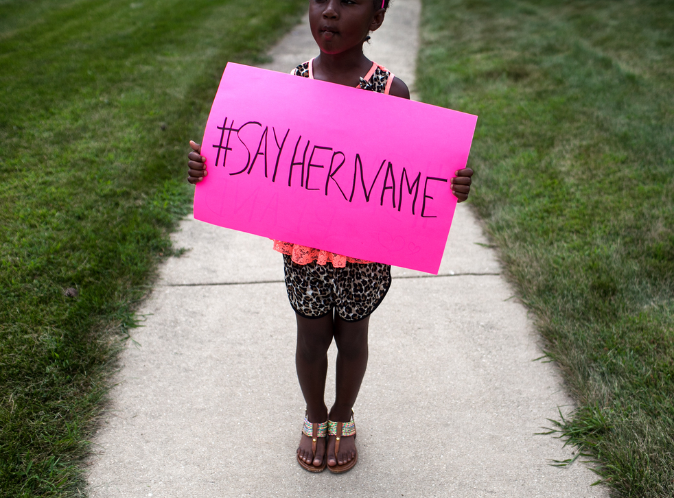 A young girl holds a sign in front of the DuPage African Methodist Episcopal Church during the funeral service for Sandra Bland