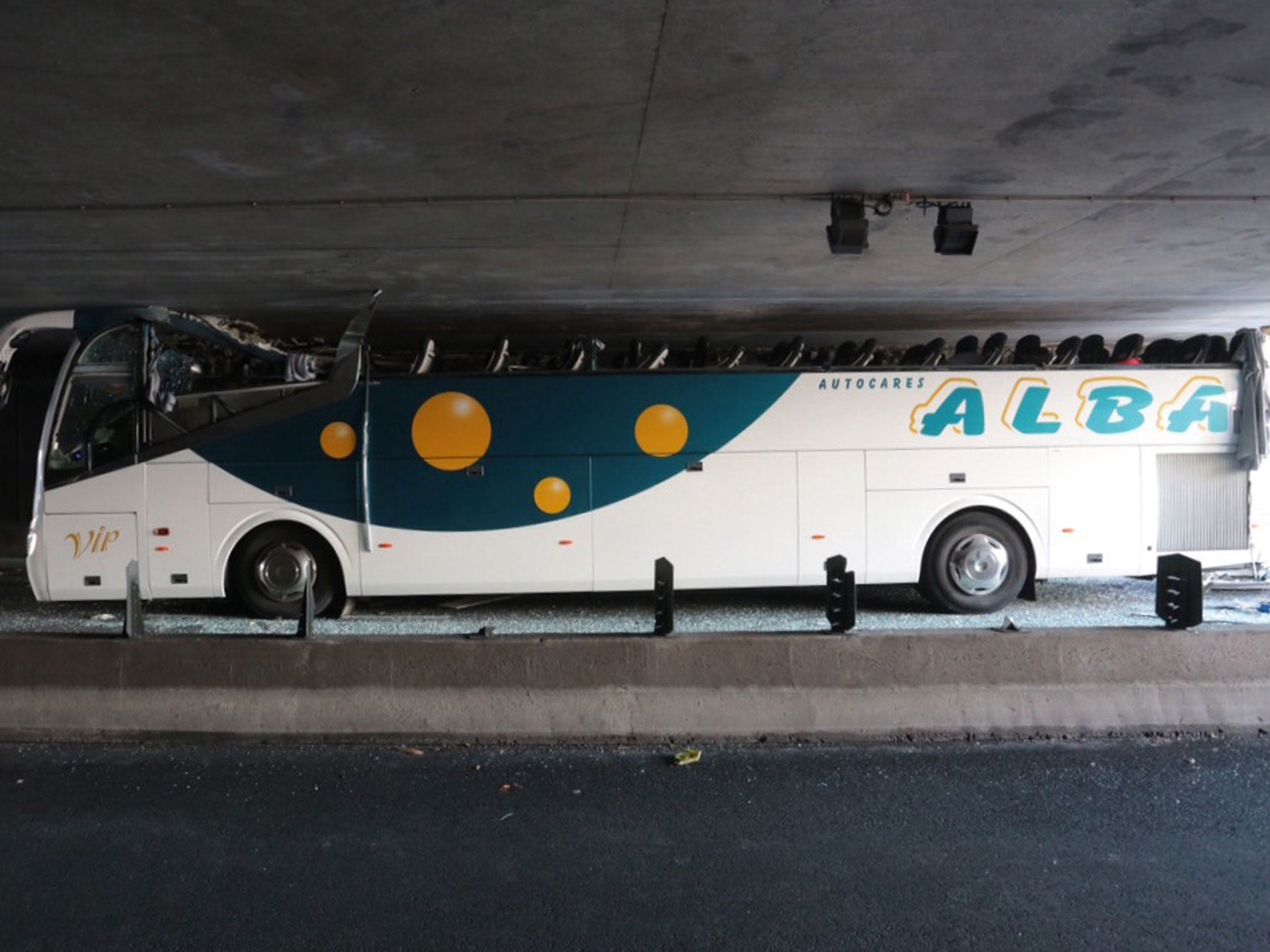 A Spanish tour bus is seen inside a mini-tunnel with its roof sheared off in France