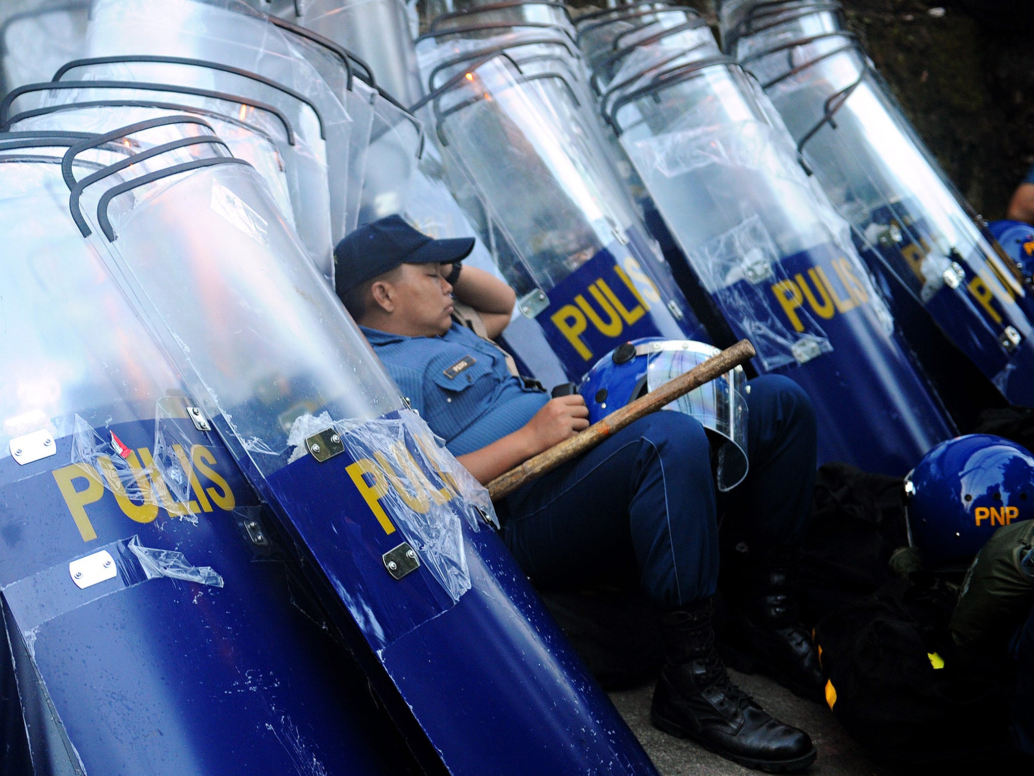 A policeman rests on riot shields before his deployment to block protesters marching towards the parliament in suburban Manila, hours before President Benigno Aquino delivers his final annual address to parliament. Aquino is expected to report on his six-year term as well as sketch a roadmap for his successor to be elected in the May 2016 elections
