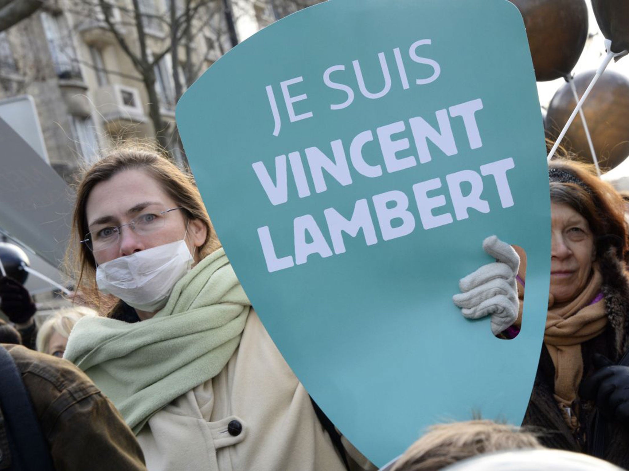 A woman holds a placard reading "I am Vincent Lambert"