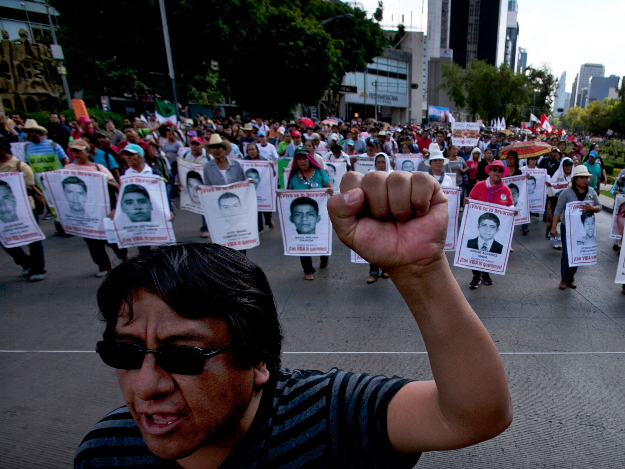 Relatives of the 43 missing students from the Isidro Burgos rural teachers college march holding pictures of their missing loved ones during a protest in Mexico City, Sunday, July 26, 2015