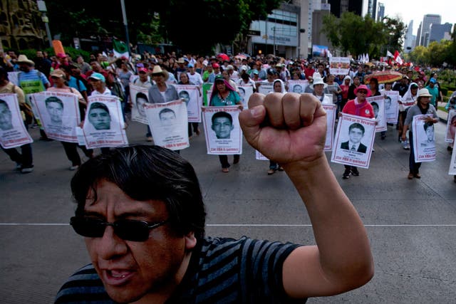 Relatives of the 43 missing students from the Isidro Burgos rural teachers college march holding pictures of their missing loved ones during a protest in Mexico City, Sunday, July 26, 2015