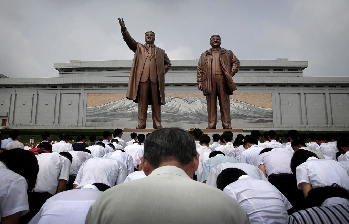 North Koreans bow in front of statues of Kim Il Sung and his son Kim Jong Il, grandfather and father of current leader Kim Jong-un, during armistice day celebrations