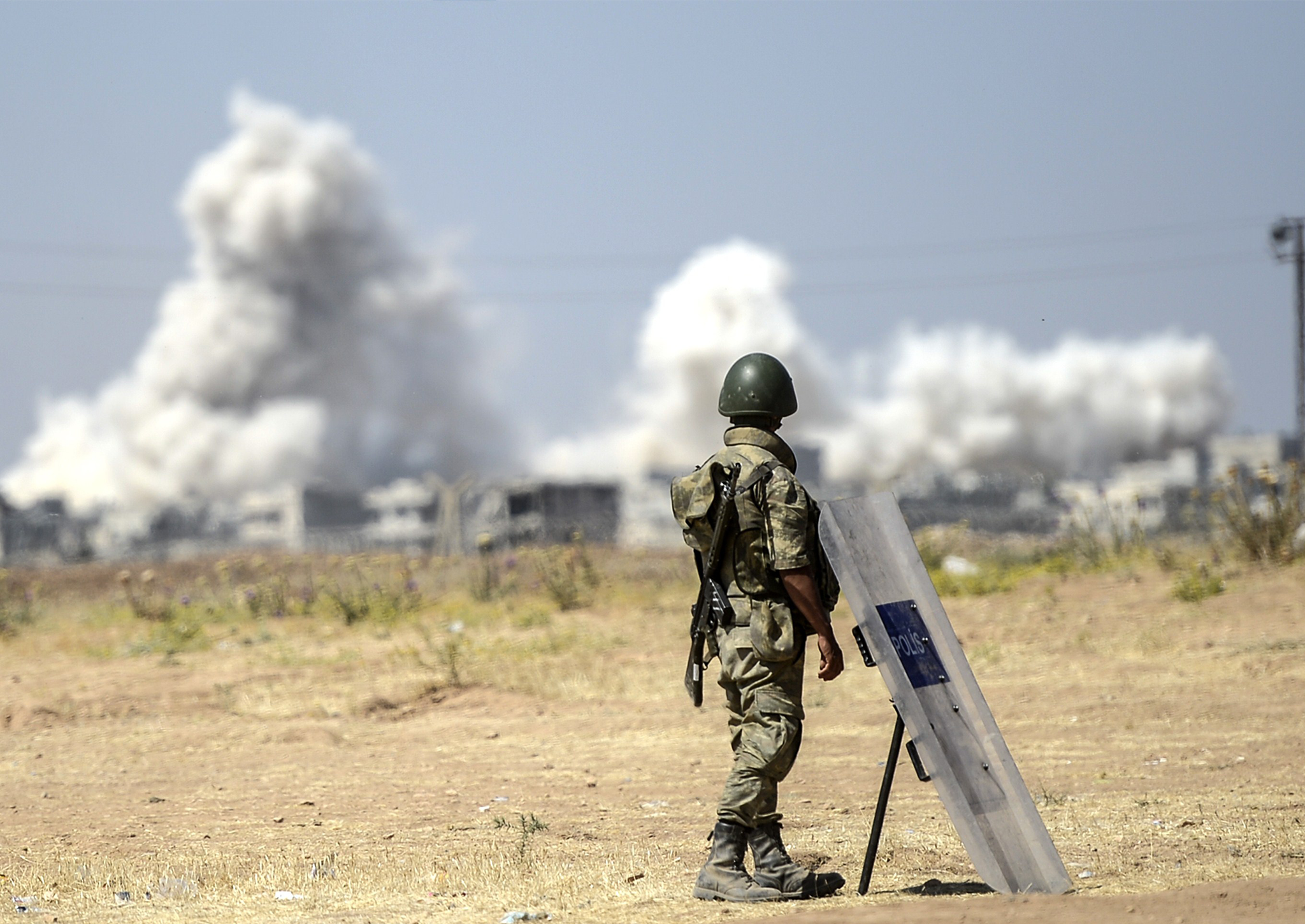 A picture taken from the Turkish side of the border in Suruc, Sanliurfa province, shows a Turkish solider standing as smoke rises from the Syrian town of Kobane