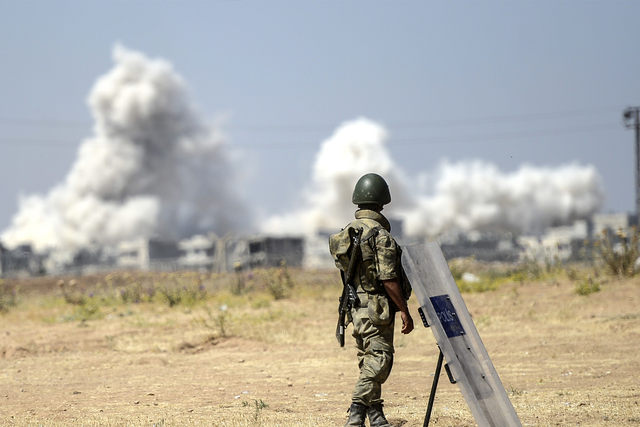 A picture taken from the Turkish side of the border in Suruc, Sanliurfa province, shows a Turkish solider standing as smoke rises from the Syrian town of Kobane