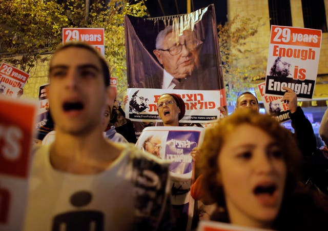 A woman shouts slogans as she stands in front of a placard depicting former Secretary of State Henry Kissinger during a protest calling for the release of Jonathan Pollard, outside U.S. Secretary of State John Kerry's hotel in Jerusalem on 2 January 2014.