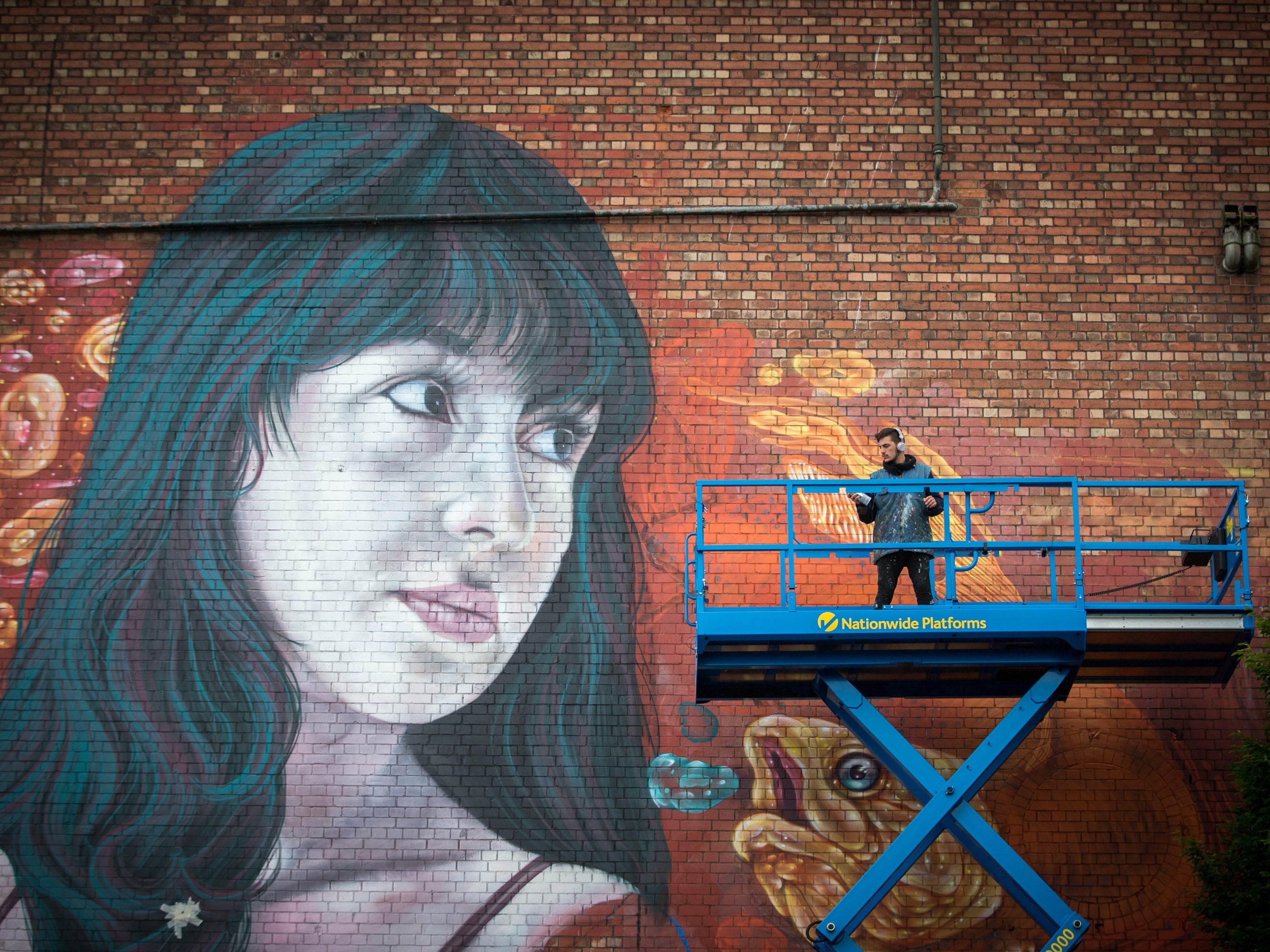 An artist works on artist Martin Ron's mural on the side of the Tobacco Factory in Bedminster