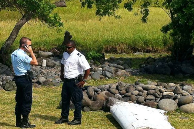 A policeman and a gendarme stand next to a piece of debris from an unidentified aircraft found in the coastal area of Saint-Andre de la Reunion, in the east of the French Indian Ocean island of La Reunion.