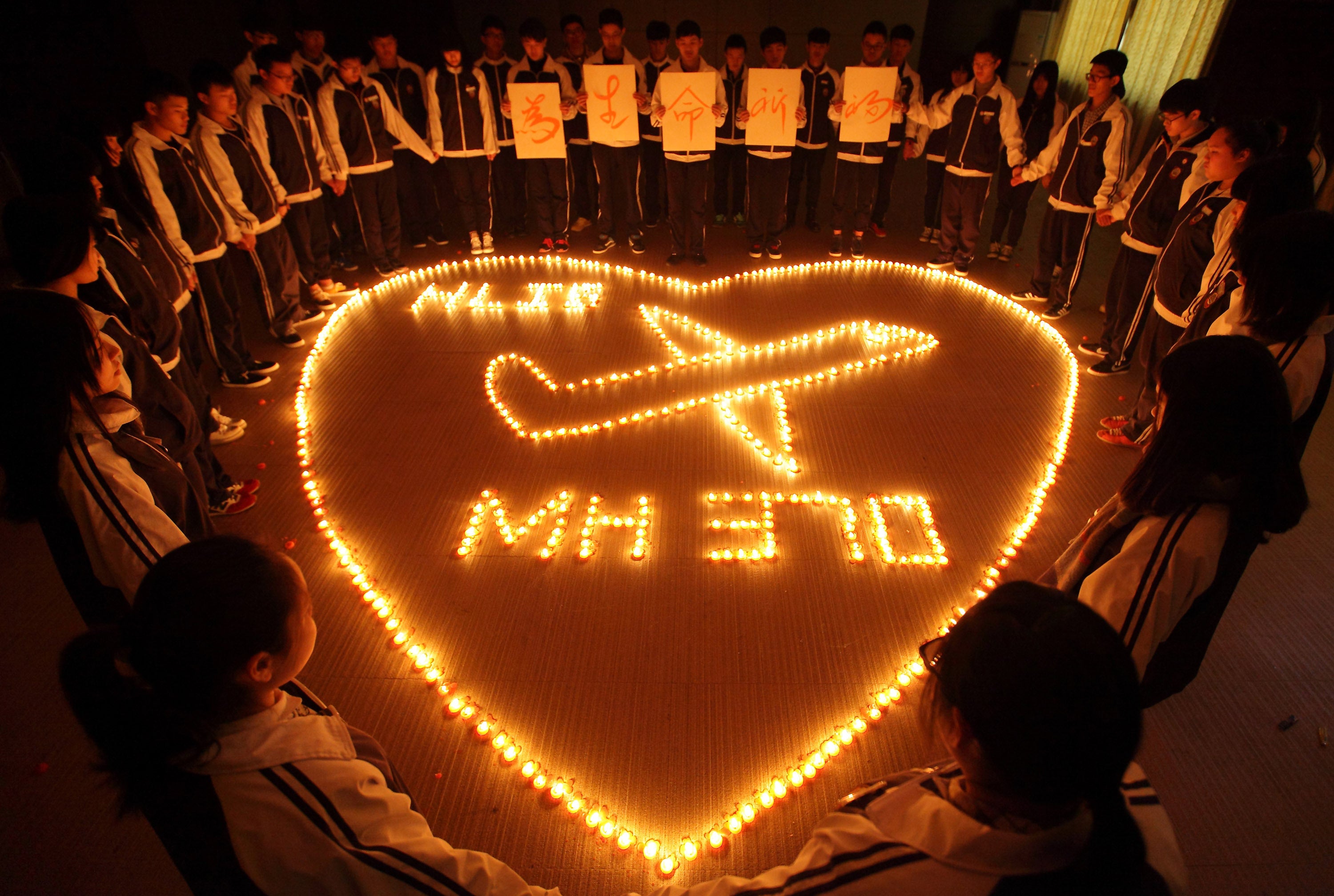 Schoolchildren hold a vigil for the missing plane and its passengers