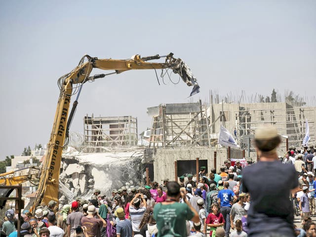Jewish settlers look on as Beit El is reduced to rubble