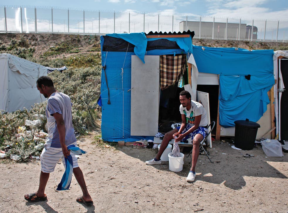 A migrant washes his clothes in a makeshift camp known as the 'Jungle'