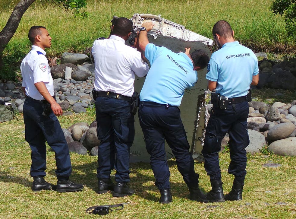 French gendarmes and police inspect a large piece of plane debris which was found on the beach in Saint-Andre, on the French Indian Ocean island of La Reunion