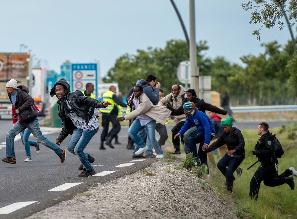 Policemen try to prevent migrants from reaching the Channel Tunnel operated by Eurotunnel in Coquelles near Calais