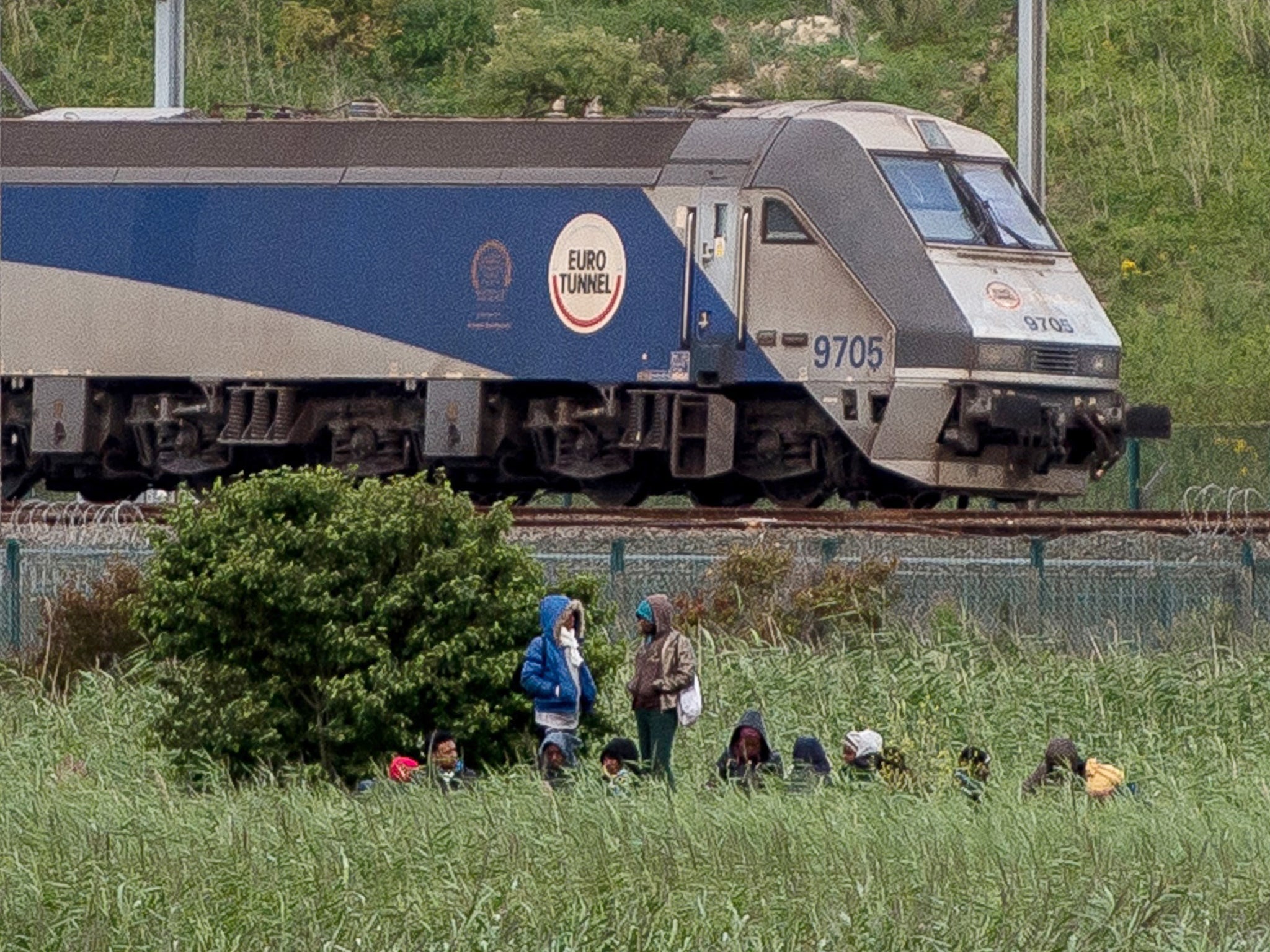 Migrants are seen near a Channel Tunnel train in Coquelles near Calais