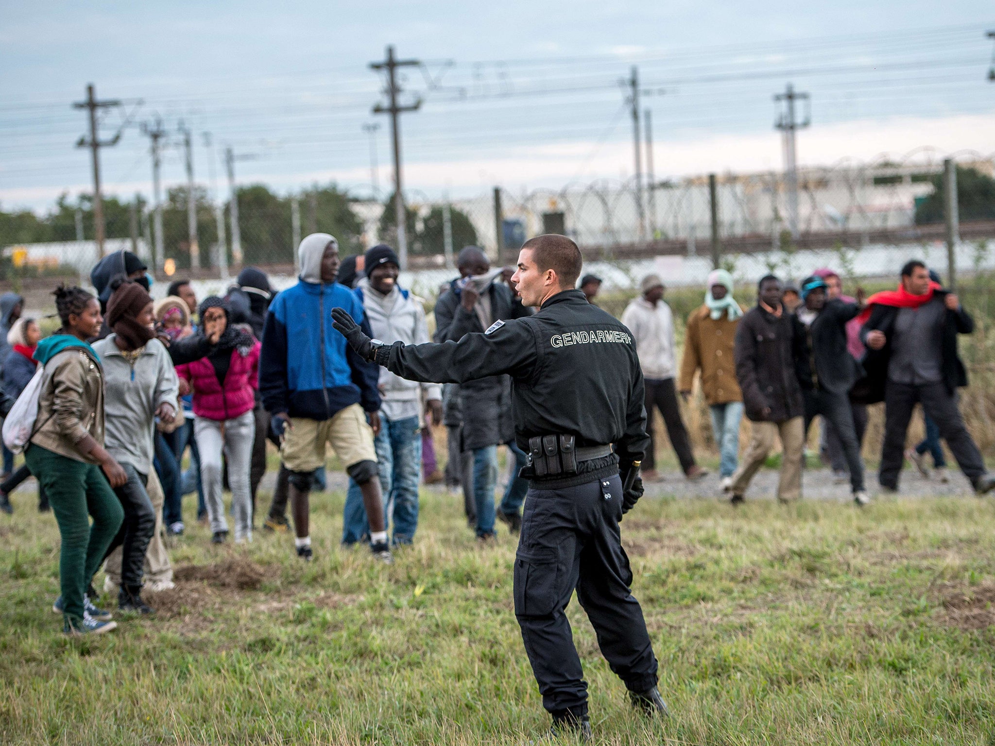 A policeman faces migrants trying to reach the Channel Tunnel operated by Eurotunnel in Coquelles near Calais (Image: Getty)