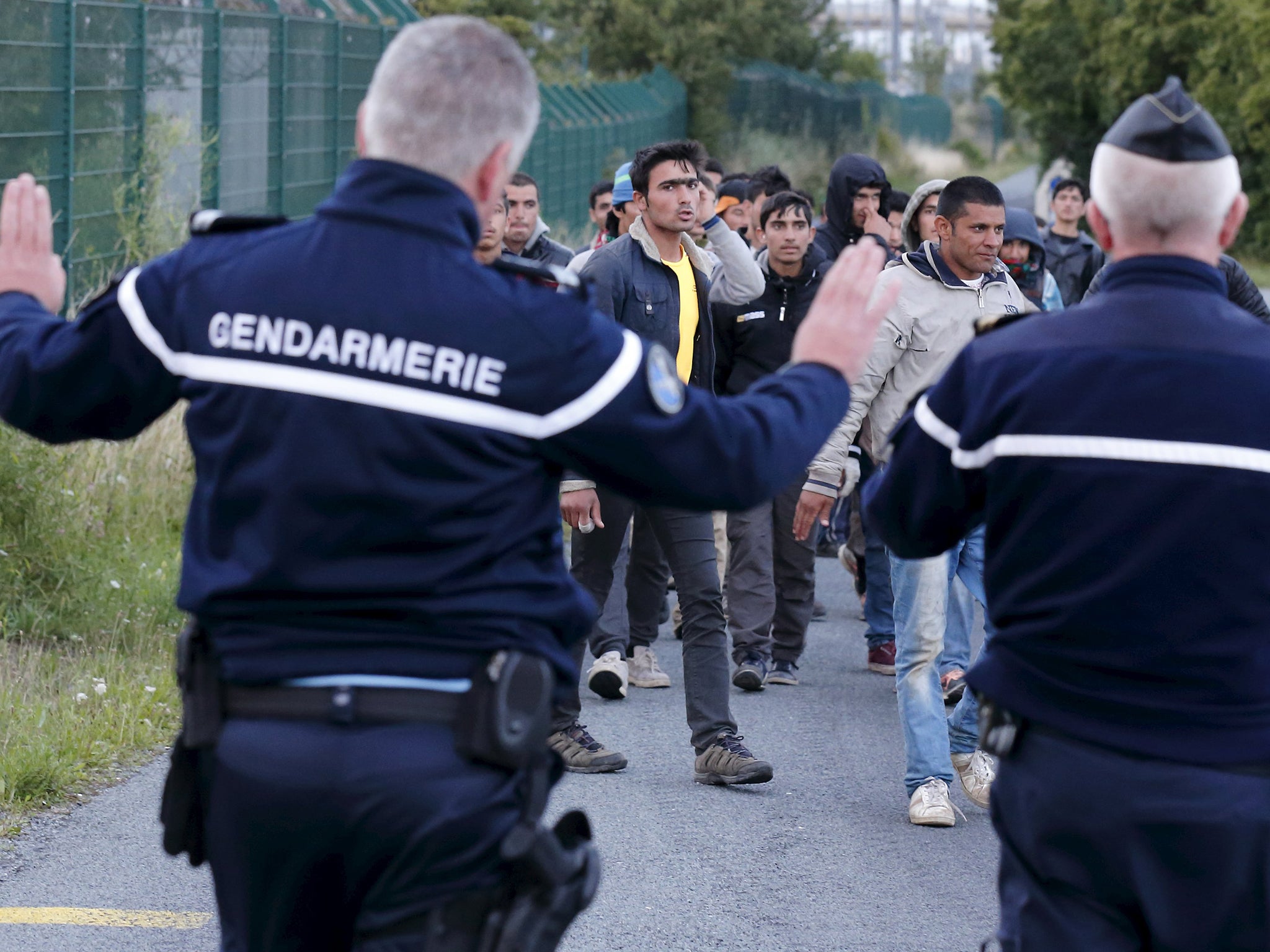 French gendarmes block migrants along a road to prevent them access to train tracks which lead to the Channel Tunnel in Frethun, near Calais