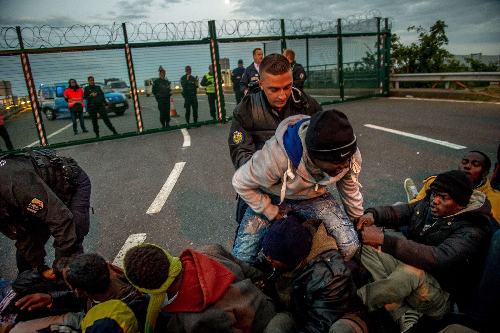French gendarmes try to separate migrants on the Eurotunnel site near the boarding docks in Coquelles near Calais