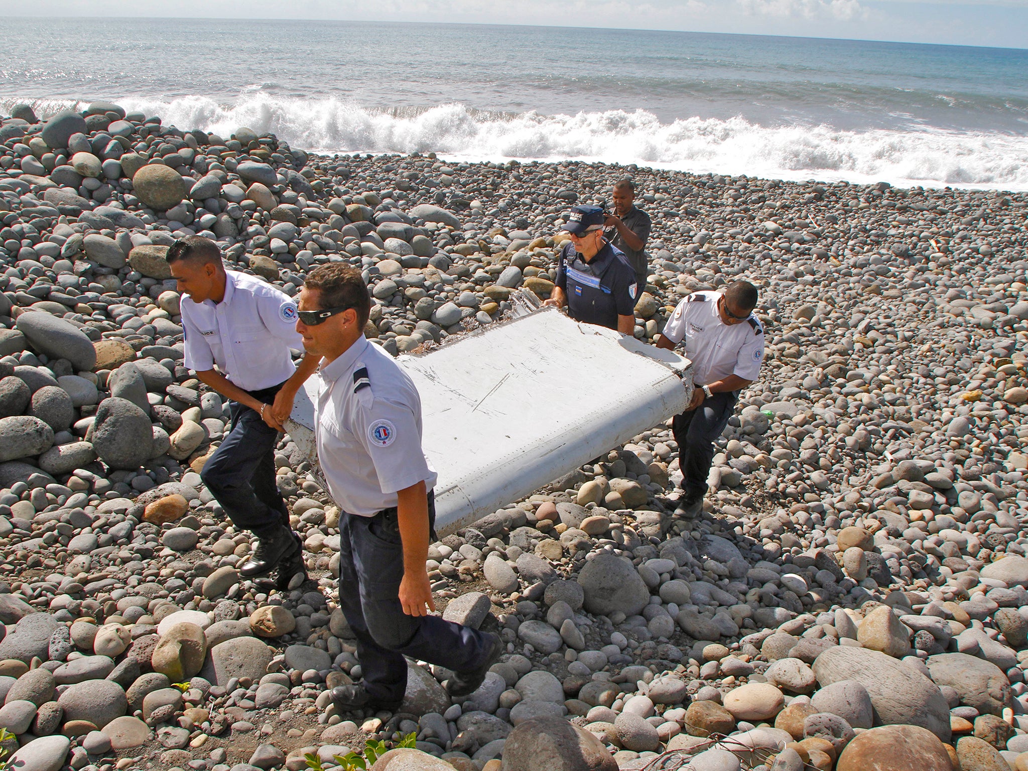 French police officers carry a piece of debris - identified as a 'flaperon' from the trailing edge of a Boeing 777 wing - in Saint-Andre, Reunion Island