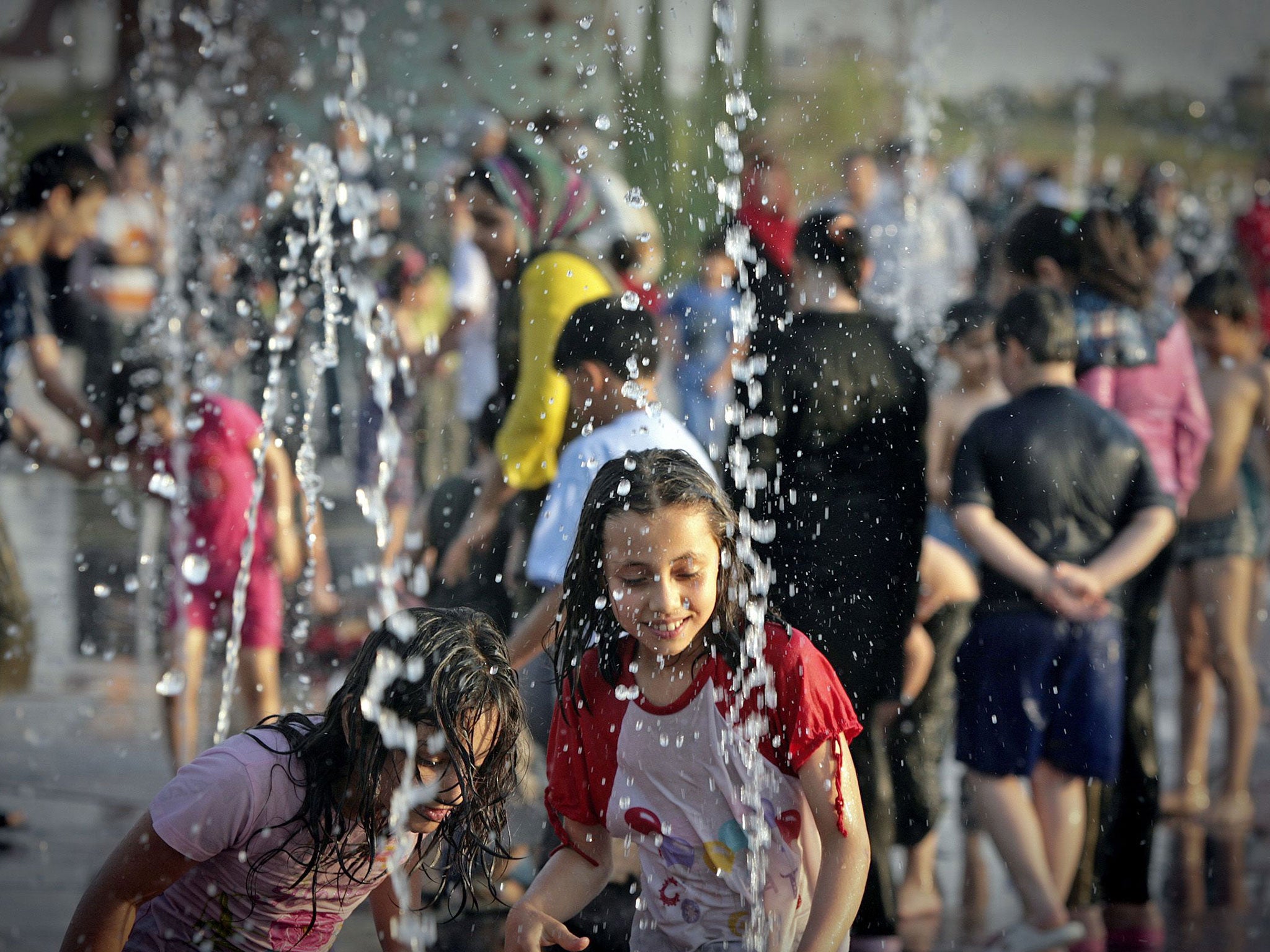 Children cool off by a water fountain in Iran