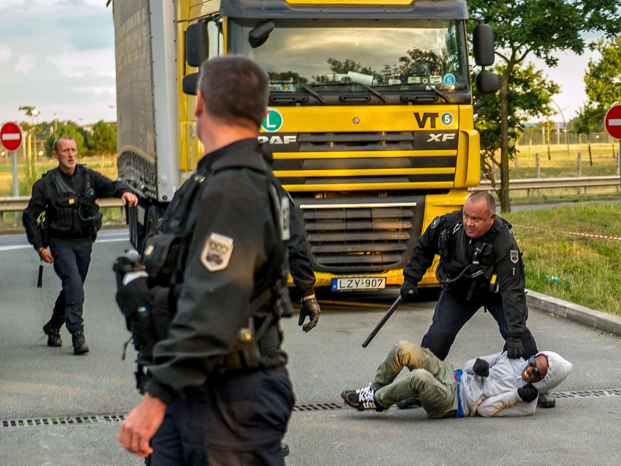 French gendarmes attempt to block a migrant after he entered the Eurotunnel site in Coquelles near Calais