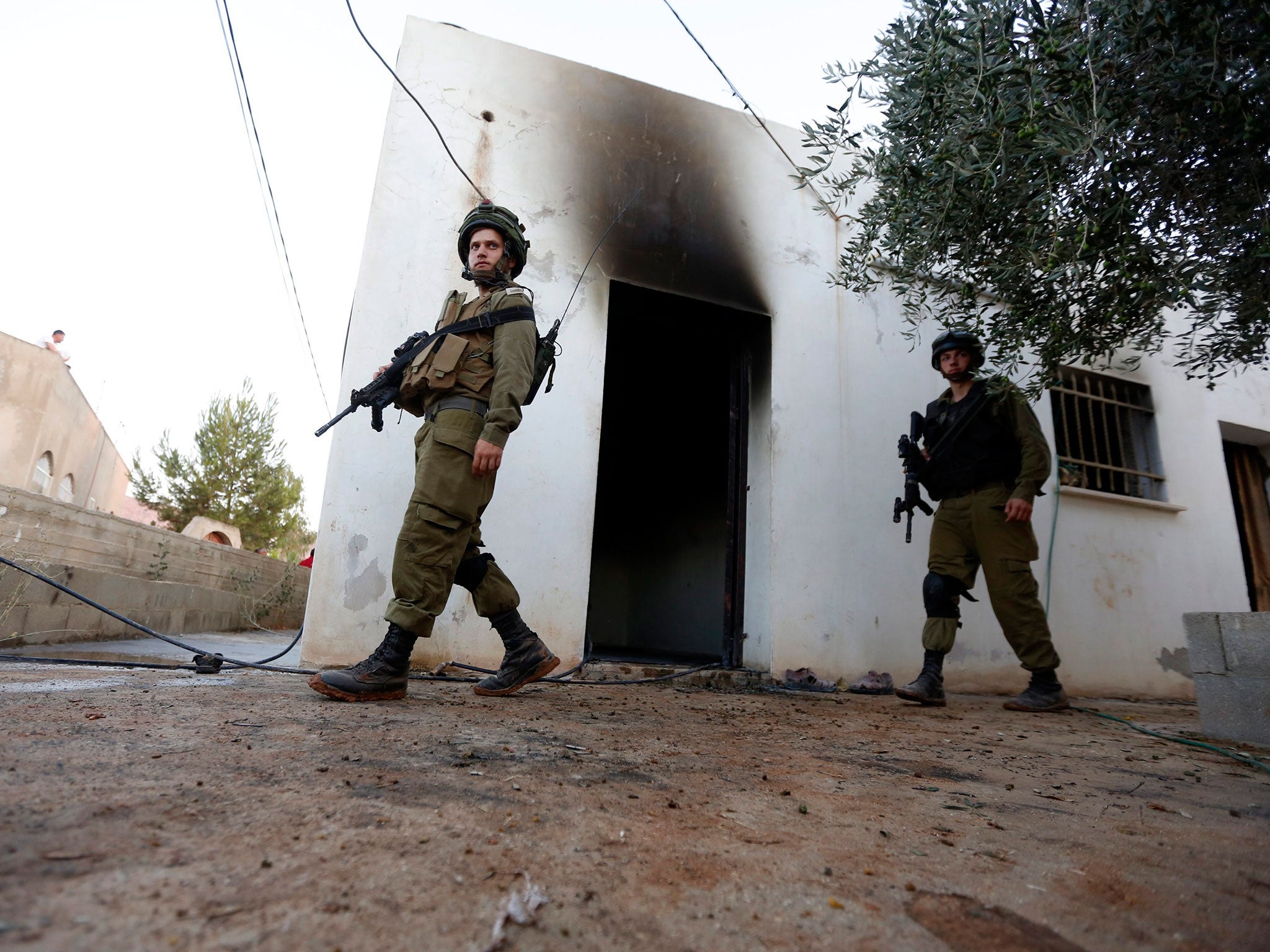 Israeli soldiers check the damage to the Palestinian fire damaged house in the West Bank village of Douma near Nablus City, 31 July 2015 (EPA)