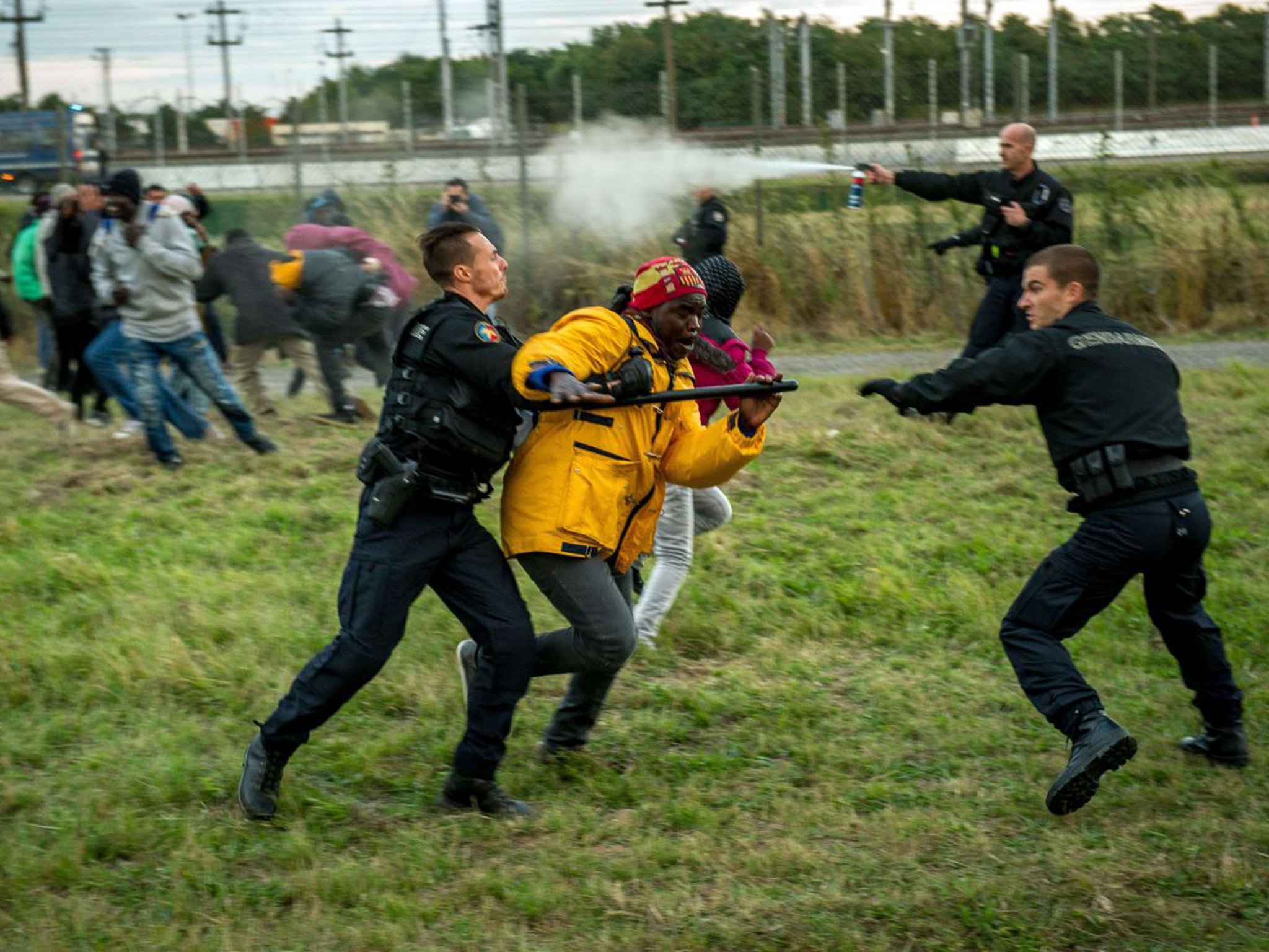 Channel clash: a migrant is held back by French police at the Eurotunnel site