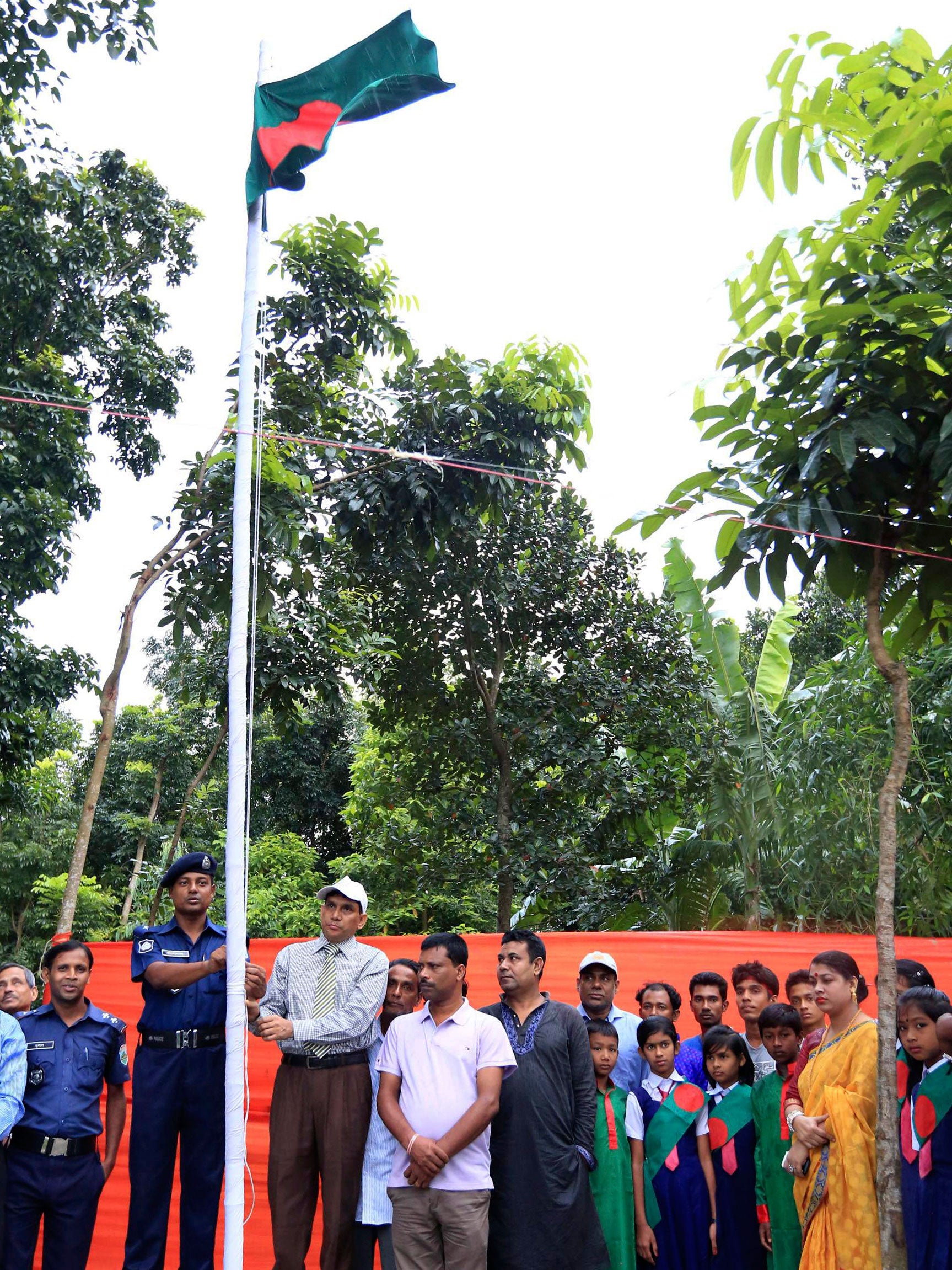 A Bangladeshi officer raises the national flag after Bangladesh and India officially exchanged enclaves