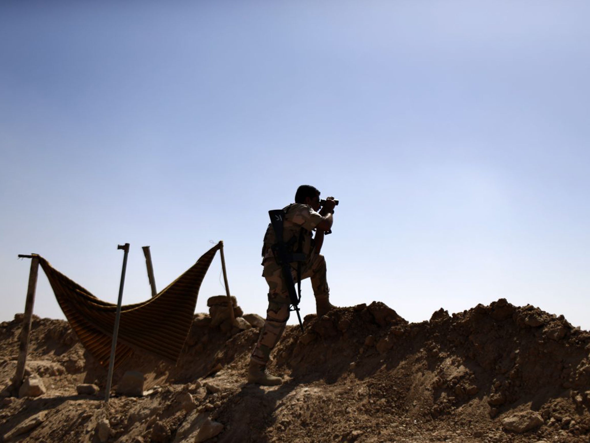 A Kurdish Peshmerga fighter monitors Isis positions on the outskirts of Makhmour, near Erbil in northern Iraq. The Kurdish-held area has now become a target for Turkish air strikes