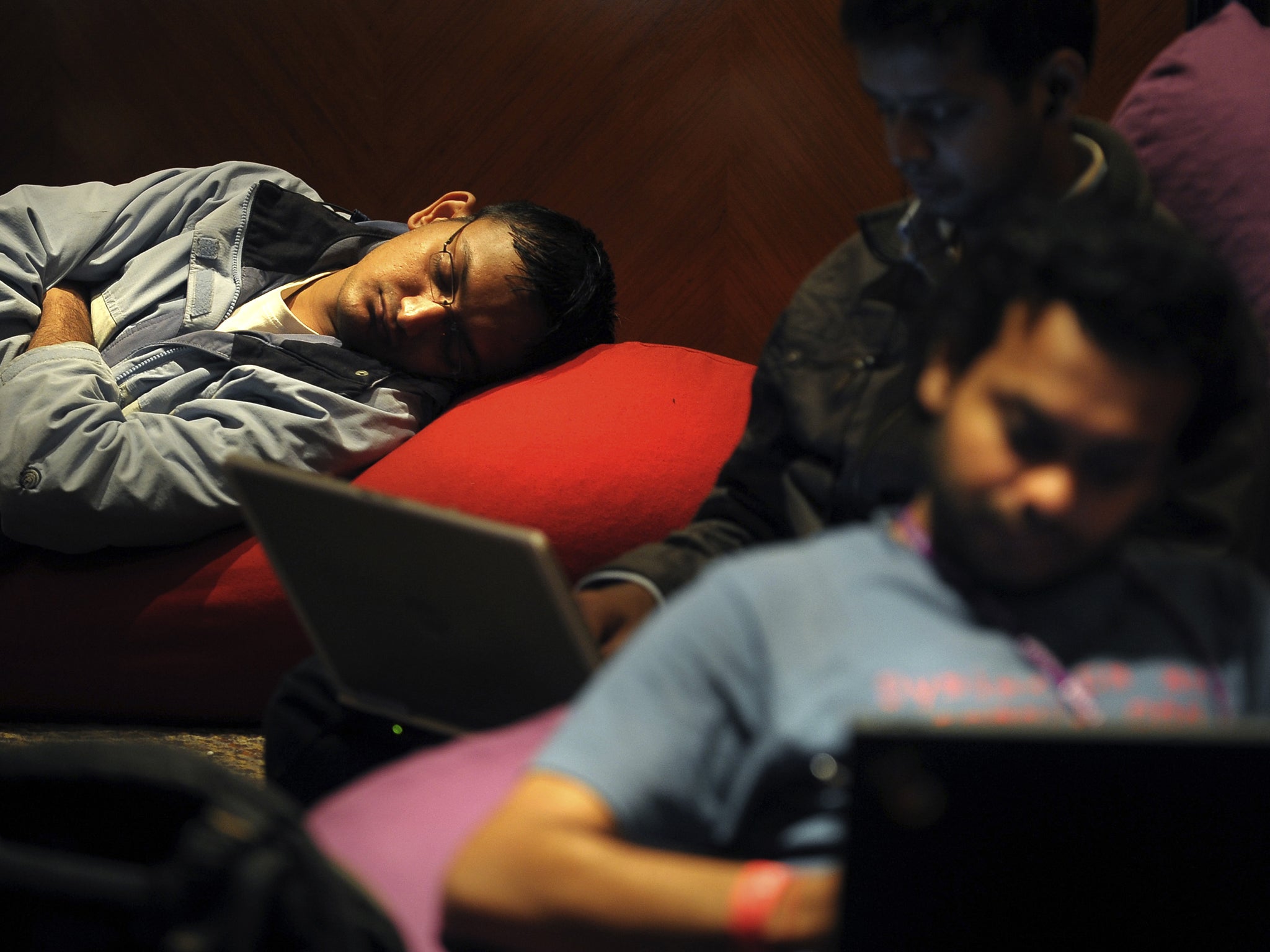 Indian IT professionals work on their laptops as others sleep during an 'Open Hack Day' programme organised by the global search engine Yahoo! in Bangalore on July 25, 2010