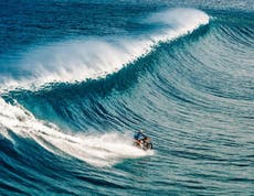 Watch a man surf a wave on a motorbike