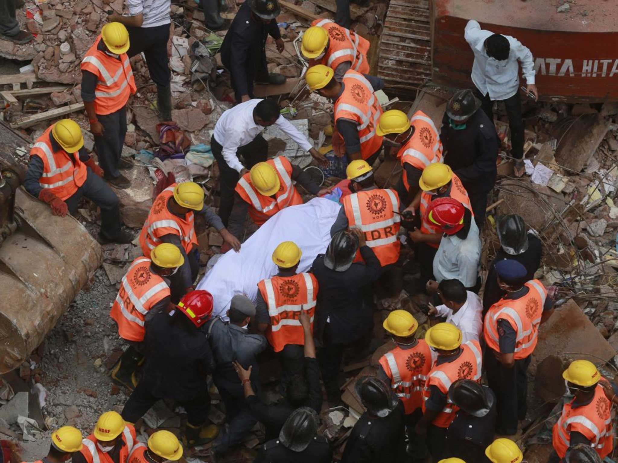 Rescue workers carry the body of a victim at the site of building collapse in Thane