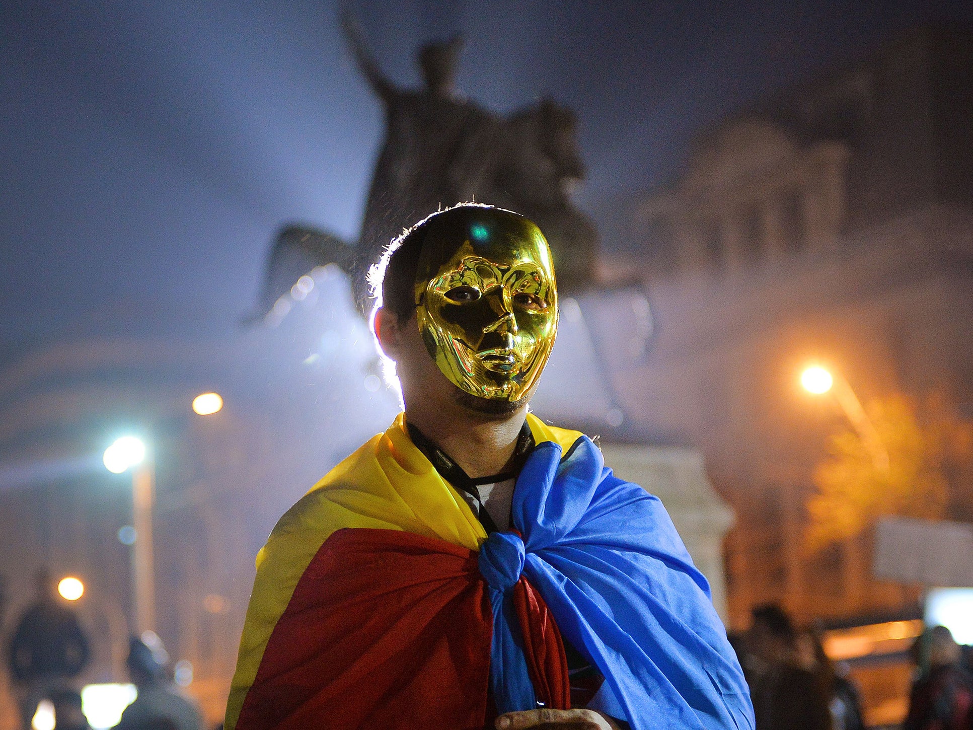 A protester wears a golden mask and Romanian flag during a demonstration in Bucharest against Gabriel Resources Rosia Montana gold and silver project
