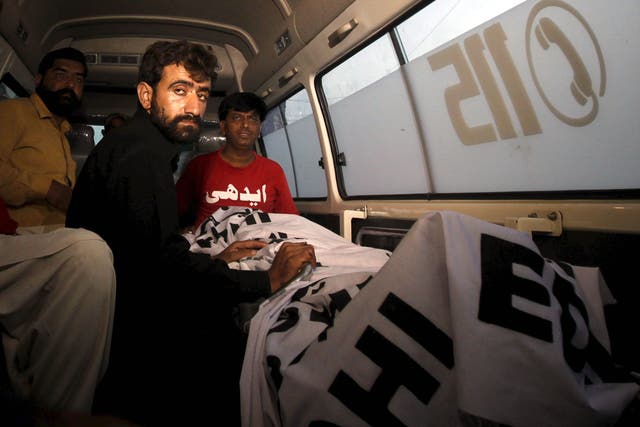 Abdul Majeed sits in an ambulance beside the body of his brother,  Shafqat Hussain