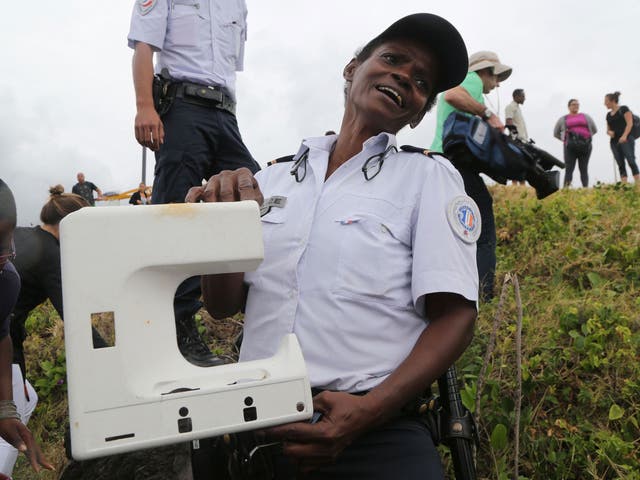 A police officer holds a piece of plastic found on the sea front of Saint-Denis, on the French Indian Ocean island of La Reunion, on August 4, 2015