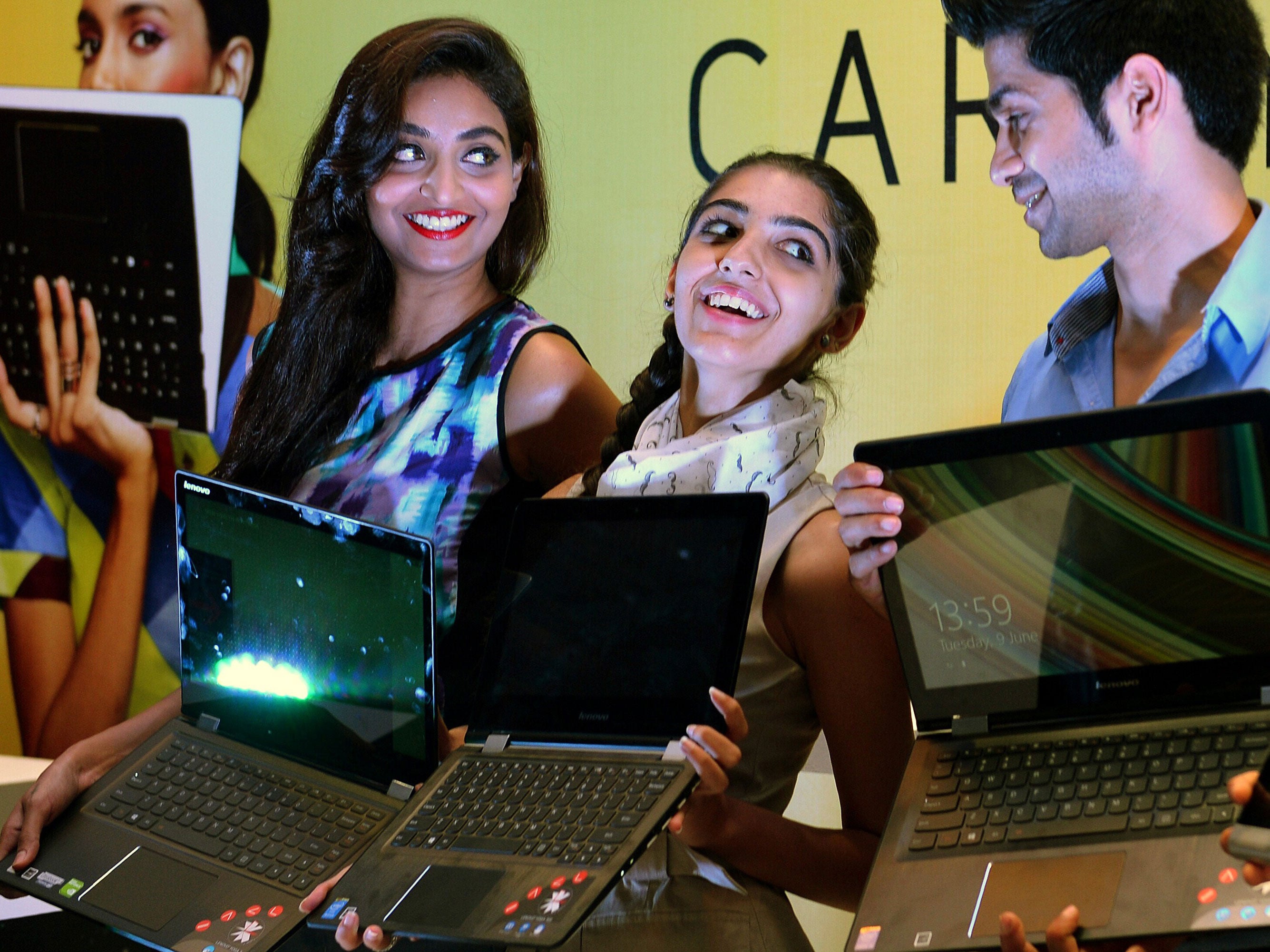 Indian models pose with the flexible 'YOGA' range of Lenovo laptops during their launch in Bangalore on June 9, 2015. Lenovo launched two models named the YOGA 300 and YOGA 500