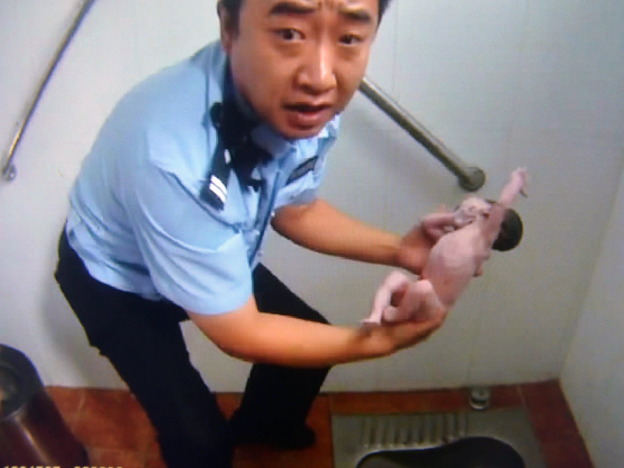 A policeman holding an abandoned newborn baby in a public toilet in Beijing. A newborn baby girl was abandoned in a Beijing public toilet and fell head-first down the pipe, reports said, after her mother apparently gave birth in the facility
