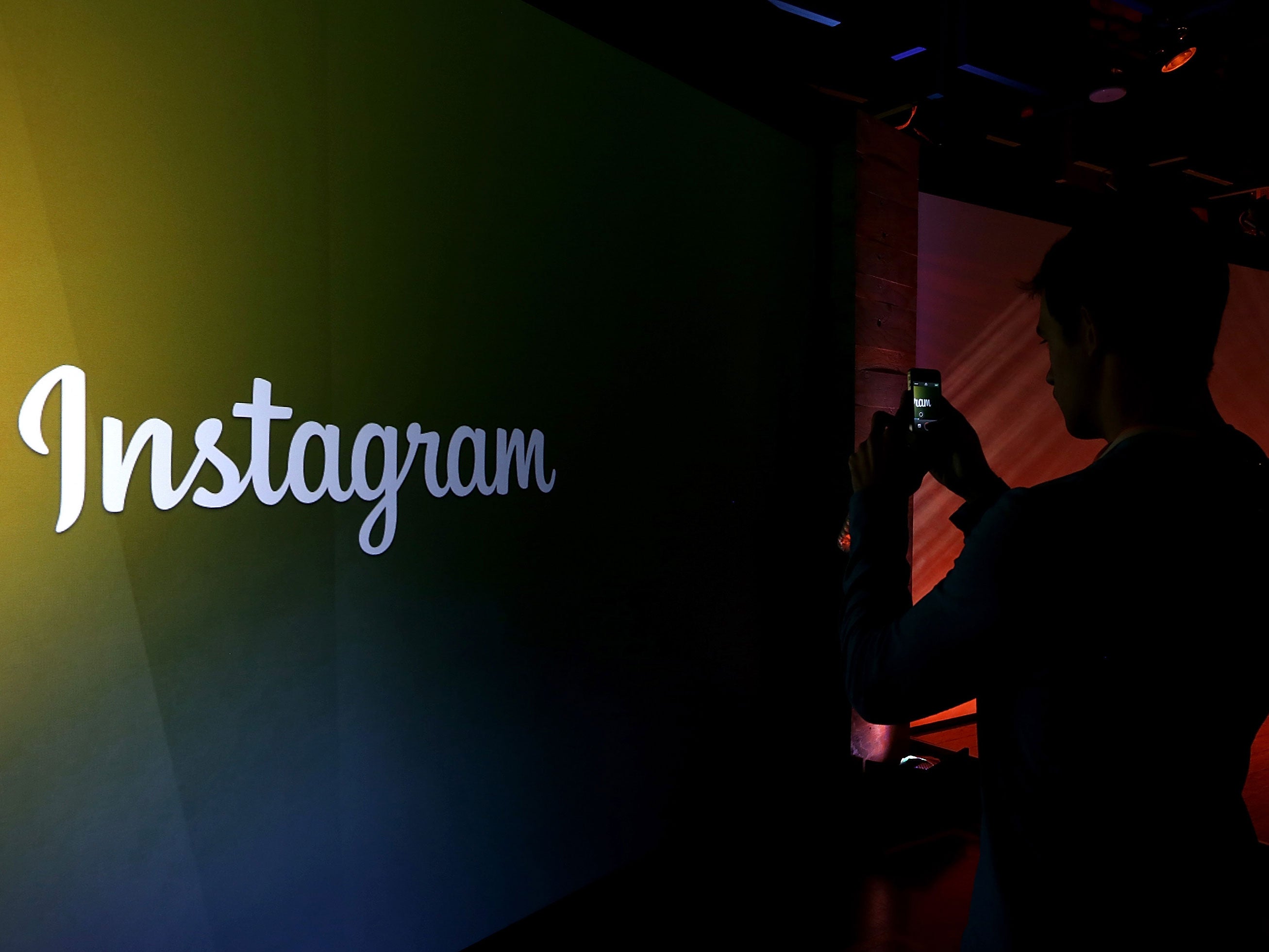 an attendee takes a photo of the instagram logo during a press event at facebook headquarters - following under username on instagram