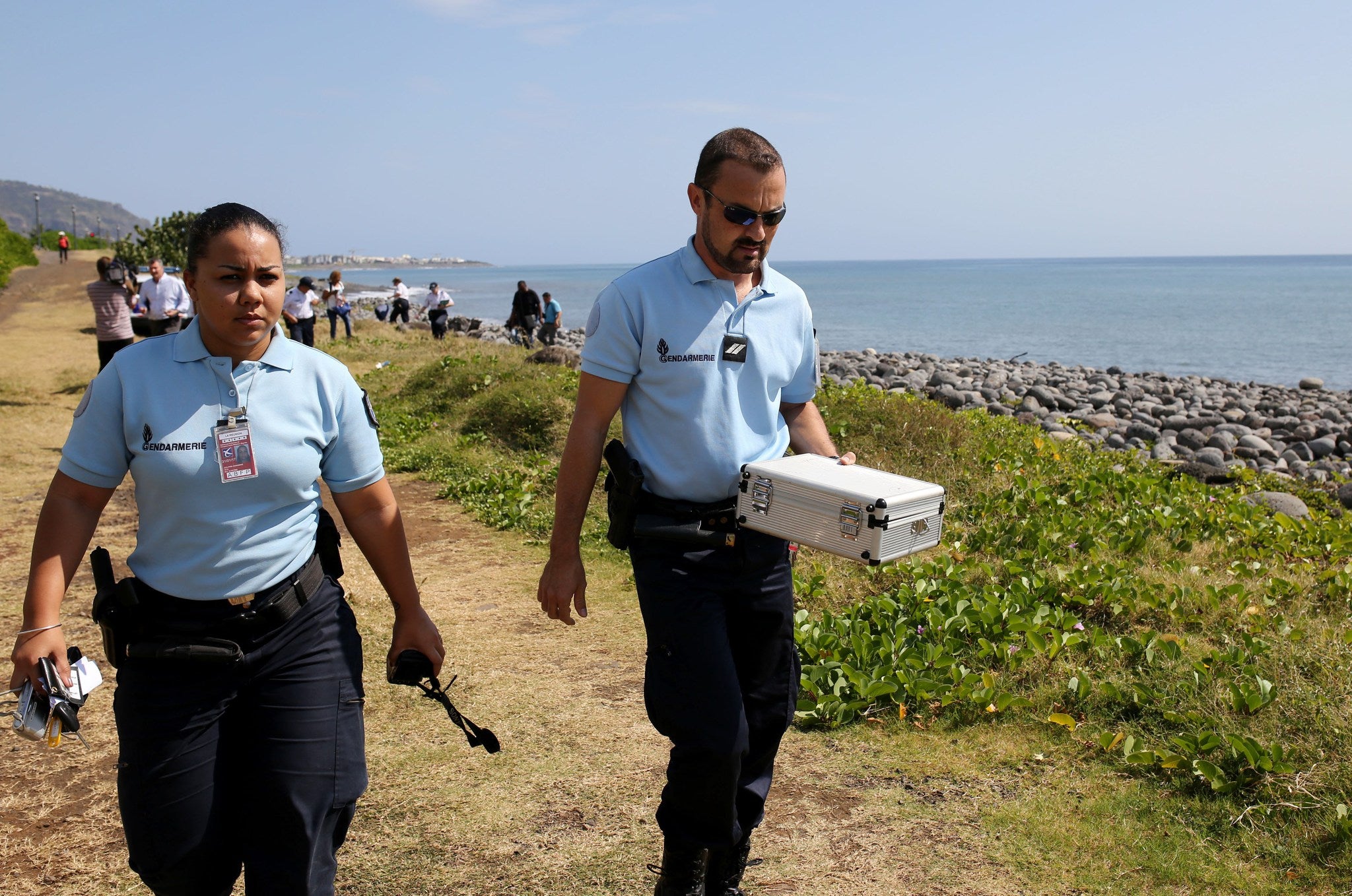 Police officers on Reunion island carry away small pieces of metallic debris, that will be examined to see if they are from MH370