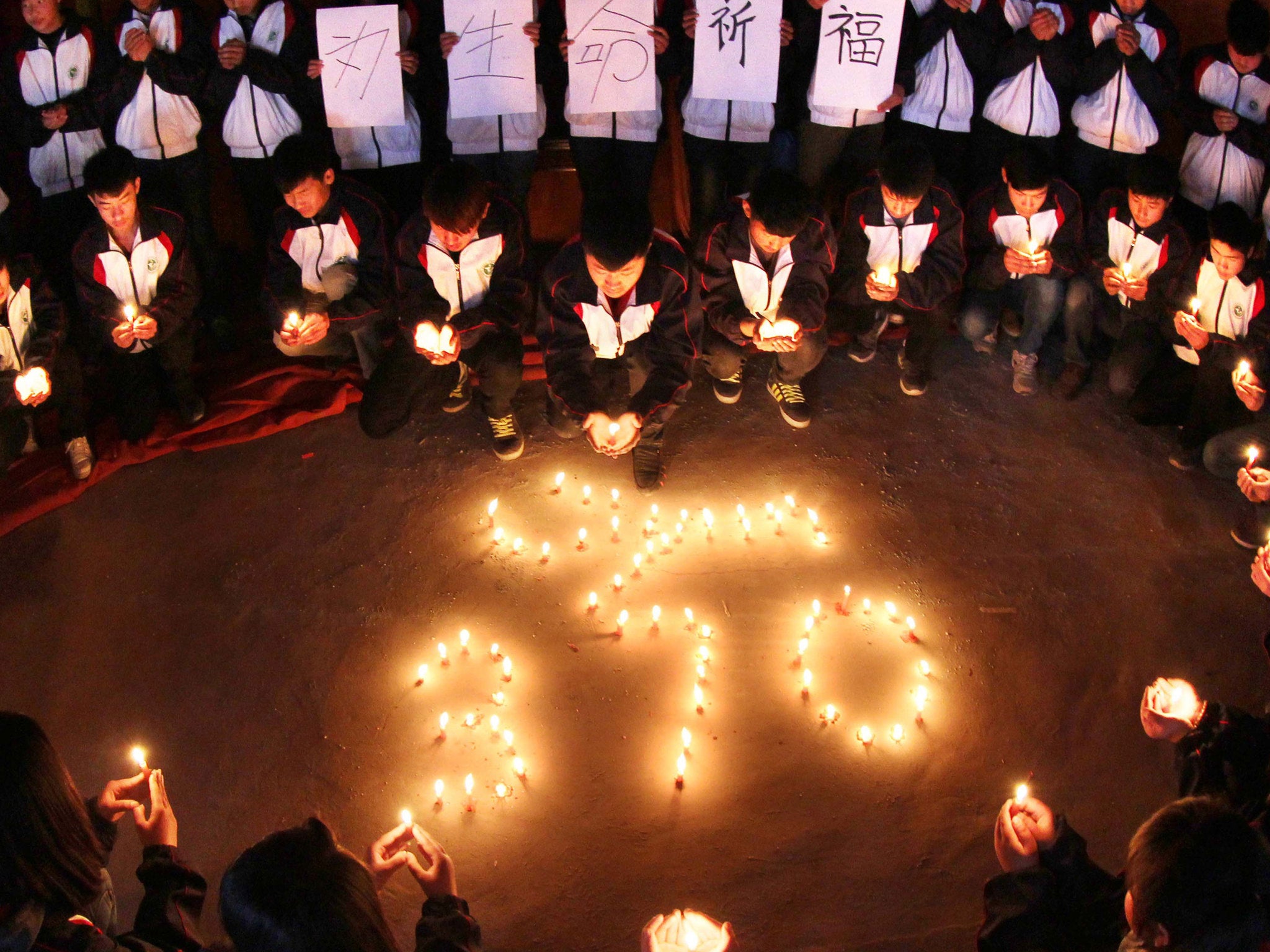 High school students hold candles during a vigil for passengers of the missing Malaysia Airline flight MH370 in China