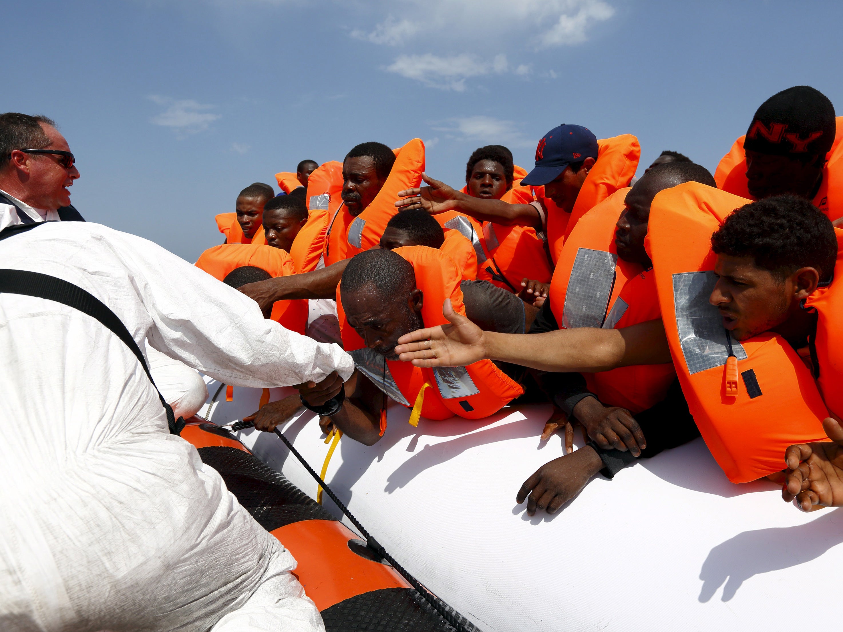 Migrants are helped to cross from their rubber dinghy to a Migrant Offshore Aid Station